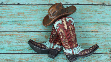 cowboy boots and hat laying on a teal background with copy space