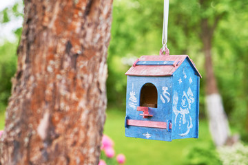Blue birdhouse hanging in the garden in summer