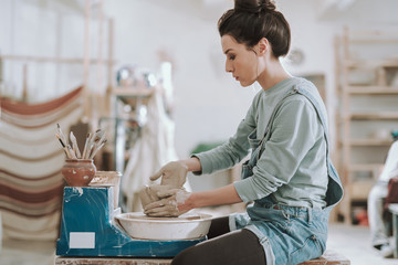 Attractive young lady working on pottery wheel