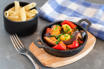 Vegetarian ratatouille with baked aubergine, zucchini, pepper in tomato sauce. Dish served with...