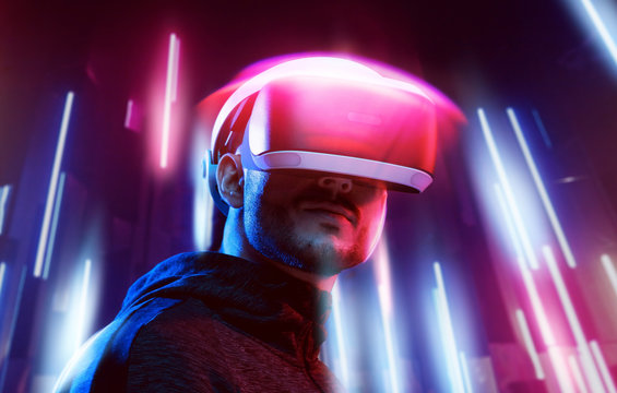 Model young man with beard in glasses of virtual reality. Augmented reality, science, future technology, people concept. VR. Futuristic 3d glasses with virtual projection. Neon blue, pink light.