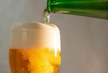 pouring beer into a glass from a green bottle