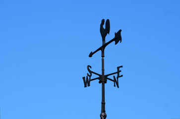 The four cardinal point on the top of a barn with blue sky.