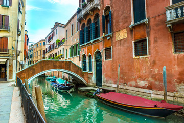 Fototapeta na wymiar Canal with boats and colorful facades of old medieval houses and bridge in Venice, Italy, Europe
