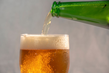pouring beer into a glass from a green bottle