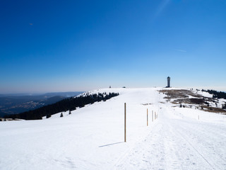 Panoramic view on snowy hill in the black forest with tower in the background and blue sky - Ski...
