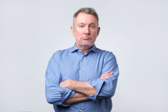 Serious Senior Man In Blue Shirt With Folded Arms