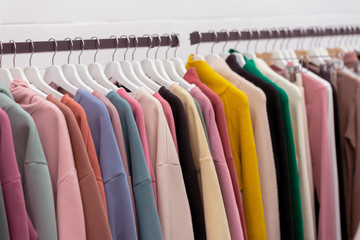 Colorful youth cashmere sweaters and hoodies, sweatshirts and on a clothes rack in store