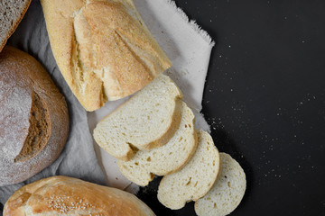 Bakery - fresh homemade sliced bread on black chalkboard background. Flat lay, top view, copy space for your text