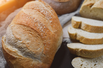 Bakery - gold rustic crusty loaves of bread on black chalkboard background. Flat lay, top view, copy space for your text