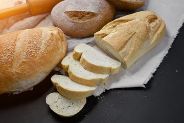 Bakery - gold rustic crusty loaves of bread and rolling pin on black chalkboard background. Flat lay, top view, copy space for your text
