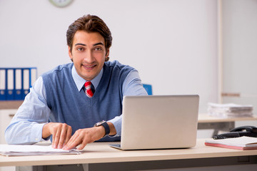 Young handsome employee working in the office 