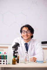 Young funny chemist in front of white board 