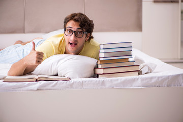 Young student studying in bed for exams