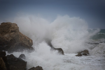 Big wave hit the rocks with splashes and spray