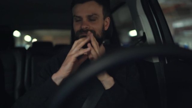 Man driving in innovative automated car using self-parking autopilot for parking on street