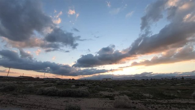 Golden sunset over rural Mojave Desert scrub landscape to blue twilight