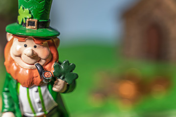 A happy leprechan in the forest in front of his gold.