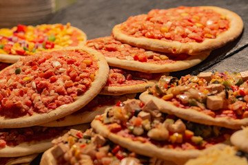 Many small hot pizzas on sale at a street market