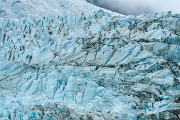 Glacial blues and dirt browns in fractured ice patterns on glacier in Drygalski Fjord, South...
