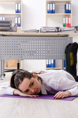 Obraz na płótnie Canvas Female employee doing sport exercises in the office 