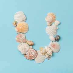 Letter 'U' from sea shells on blue background. Alphabet in marine style. Vacation ABC. 