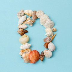 Letter 'D' from sea shells on blue background. Alphabet in marine style. Vacation ABC. 