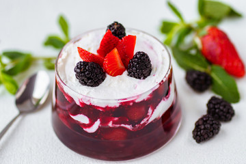 trifle, layered mouse in portioned glass jar. seasonal fresh dessert of sponge cake, ripe berries, custard and fruit juice