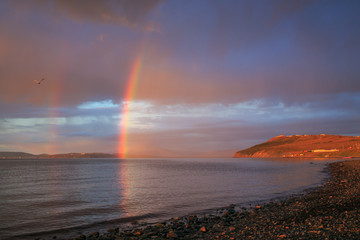A picturesque evening landscape with a rainbow over a wide river. Beautiful northern nature. Anadyr...