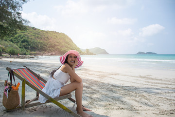 Beautiful young Asian woman happy, smile while relaxing sitting in sun chairs on beach on summer holidays vacations. Concept freedom, Lifestyle, tourism, holiday.