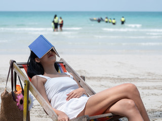 Beautiful young Asian woman sleeping relaxing in sun chairs on beach on summer holidays vacations....