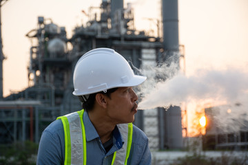 Engineers male smoking e-cigarette in front of power plant. Energy power station area. Relax from work concept