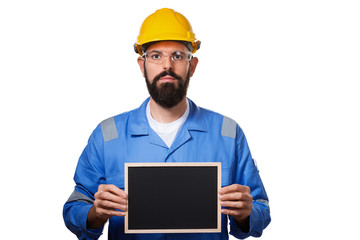 Builder worker in protective construction helmet holding black chalk board with space for informational text, isolated on white background.