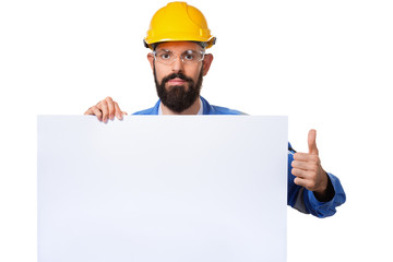 Builder worker in protective construction helmet raising his thumbs up and holding white advertising board with copy space, isolated