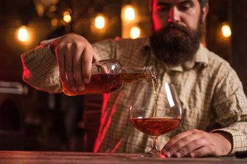 Degustation, tasting. Man with beard holds glass of brandy. Stop drinking.