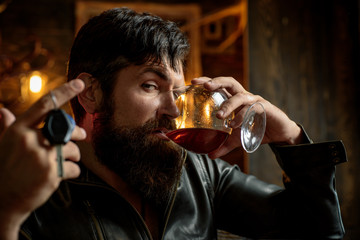 Man with beard holds glass brandy. Macho drinking. Confident man with car keys in his hand. Do not...