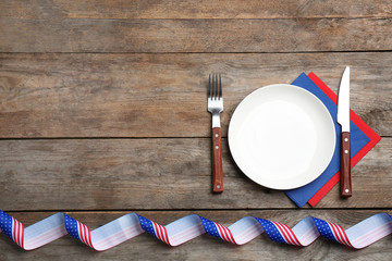 Patriotic table setting with traditional USA colors on wooden background, flat lay. Space for text