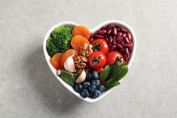 Bowl with products for heart-healthy diet on grey background, top view
