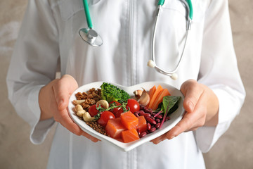 Doctor holding plate with products for heart-healthy diet, closeup