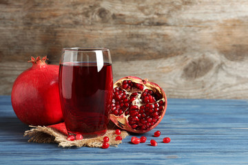 Glass of pomegranate juice and fresh fruits on table against wooden background, space for text