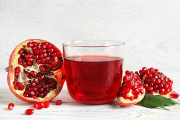 Glass of pomegranate juice and fresh fruits on wooden table