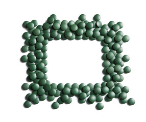 Frame of green spirulina pills on white background, top view with space for text