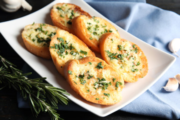 Plate with delicious homemade garlic bread on table