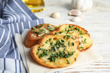 Slices of tasty garlic bread with herbs on table