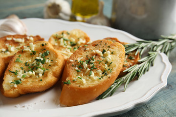 Plate with delicious homemade garlic bread on table, closeup