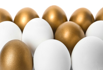 Golden eggs among others on white background