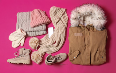 Fototapeta na wymiar Flat lay composition with warm clothes for winter vacation on color background