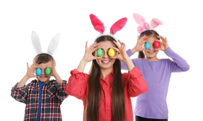 Cute family in bunny ears headbands with Easter eggs near eyes on white background