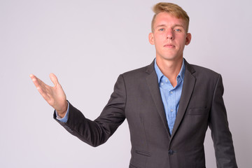 Portrait of young blonde businessman with suit showing something