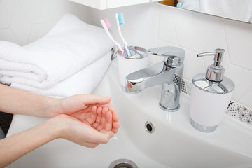 morning hygiene. Child wash his hands. Bath preparation. White interior of bathroom. Toothbrush and soap dispenser. Details of bathroom